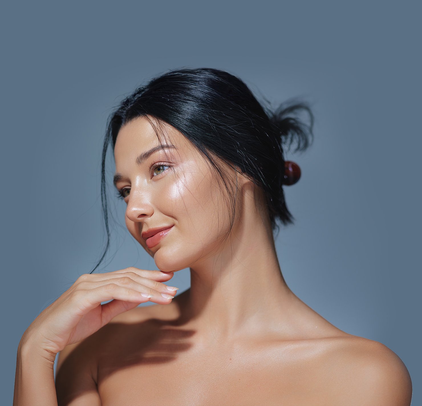 Woman with beautiful vibrant skin touching face and looking into the distance